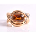An orange topaz and diamond ring centred with a cushion-cut orange topaz weighing approximately 3.94
