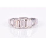 A platinum and diamond ring set with three emerald-cut diamond to centre and two to each shoulder,