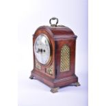 A 19th century Regency walnut bracket clock with arched top above the circular enamel dial, with