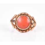 A yellow metal and coral ring set with a round cabochon coral, the coral approximately 9 mm