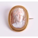 A yellow metal and shell cameo brooch the finely carved stone depicting a female in profile,