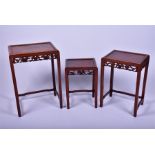 A set of three Chinese hardwood nesting tables with burr veneered top plaques, above carved and