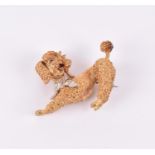 A yellow gold novelty poodle brooch in the form of a stretching dog, with sapphire eyes and a