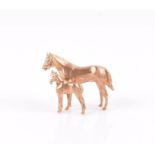A 14ct yellow gold horse brooch composed of a naturalistically modelled adult standing next to a