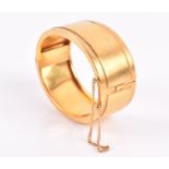 A yellow metal hinged bangle of smooth design, unmarked, internal diameter 5.3 cm, 68 grams.