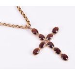 A yellow metal and garnet cross pendant open-backed mount set with nine garnets, suspended on a