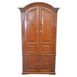 A late 18th century Continental two-sectional cherrywood armoire with arch top and bracket base, the
