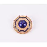 A yellow metal and enamel brooch of circular form, centred with a cobalt blue piece of enamel