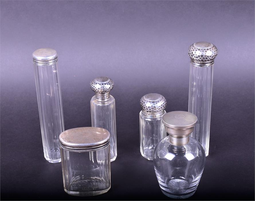 A group of silver topped dressing table bottles comprising a glass perfume bottle with engine turned