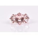 A 9ct rose gold and morganite ring set with three oval-cut morganites, largest approximately 11 x