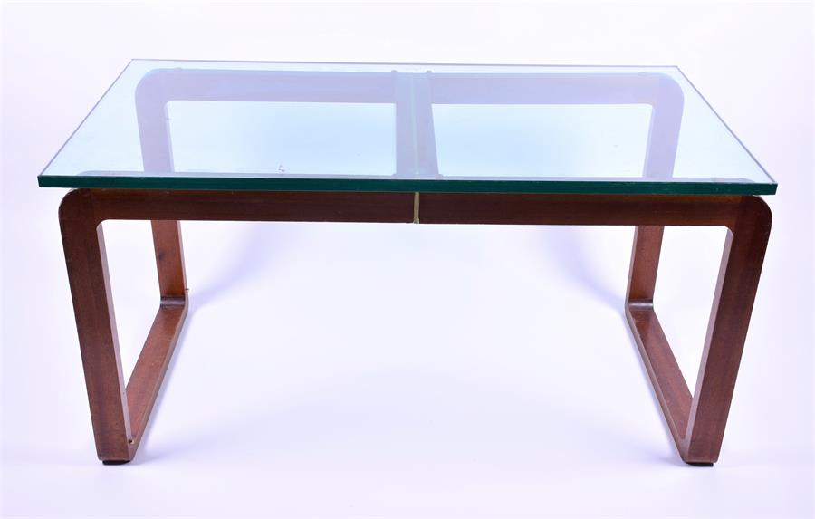 A 1970s-80s teak, metal and glass dining table, with U-shaped teak legs joined by a brass-faced