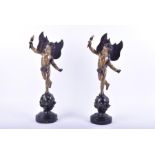 A pair of decorative cast metal figures of winged cherubs each figure standing upon a starred globe,