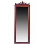 An early 20th century carved mahogany mirror the full length bevelled glass within a wooden frame,