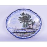 A large 19th century Delft wall plaque decorated centrally with a detailed riverside landscape