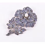 A white metal and blue sapphire floral brooch set with round-cut stones, centred with a pearl, 6.4