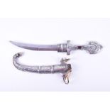 A Middle Eastern dagger & scabbard with curved blade, the brass handle with silvered detail and