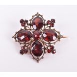 A late 19th / early 20th century yellow metal and garnet brooch set with faceted garnets and four