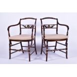 A pair of Regency style stained oak armchairs each with caned seats, applied brass collars and