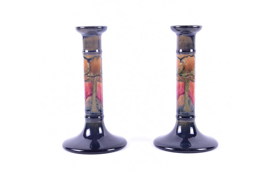 A pair of William Moorcroft pillar candlesticks in the Eventide pattern decorated with a band of