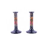 A pair of William Moorcroft pillar candlesticks in the Eventide pattern decorated with a band of