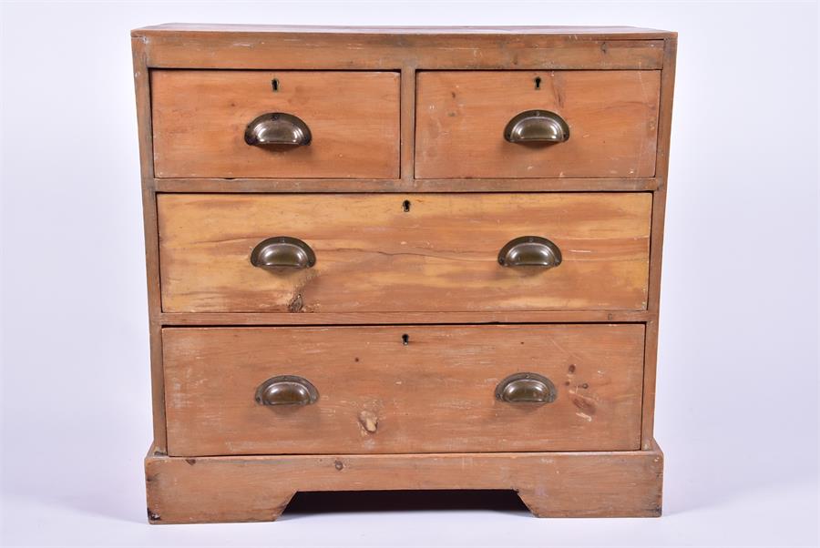 An early 20th century pine small chest with two short over two long drawers, the brass handles