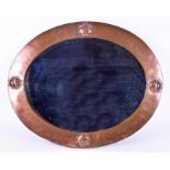 An early 20th century Arts & Crafts copper wall mirror labelled Liberty of oval form, framed in