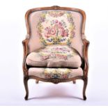 A large French walnut curved-back armchair with embroidered upholstery, on carved cabriole front