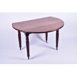 A Victorian mahogany drop leaf circular table on turned and fluted legs, terminating on brass
