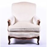 A French walnut low armchair  with cream upholstery on carved scroll front legs, 74 cm wide.