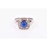 An 18ct white gold, diamond, and sapphire ring set with an oval cabochon sapphire, within a