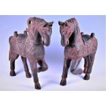 A decorative pair of Chinese carved hardwood standing horses with incised and stained detail and