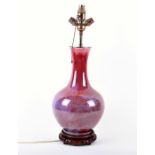 A Ruskin style porcelain lamp with sang de boeuf glaze with blue and purple tints, supported on a