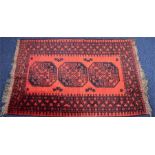 A small Turkish rug  with three central medallions on a red ground within a repeating geometric