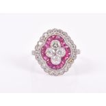 A diamond and ruby cluster ring set with a quatrefoil cluster of round brilliant-cut diamonds,