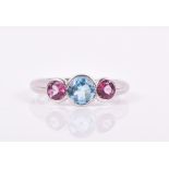 An 18ct white gold, blue and pink topaz ring set with a round-cut blue topaz flanked with two