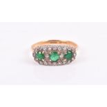 An 18ct yellow gold, diamond, and emerald cluster ring set with three round-cut emeralds within