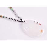 A Chinese green and white jade necklace the white pendant engraved with a figure of a woman,