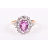 An 18ct yellow gold, diamond, and pink sapphire cluster ring set with a mixed oval-cut pink sapphire