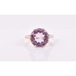 A yellow metal and amethyst ring set with a faceted round-cut pale lilac amethyst, shank unmarked (