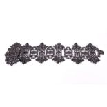 A 19th century Berlin ironwork bracelet composed of stylised panels with pierced foliate detail,