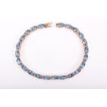 A 9ct yellow gold and blue topaz bracelet set with oval-cut topaz and round-cut diamonds, 17 cm