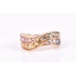 A 9ct yellow gold and multi-coloured sapphire ring in a crossover mount, set with pink, yellow,