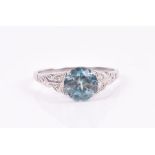 A 9ct white gold, blue zircon, and diamond ring set with a round-cut natural zircon, the shoulders