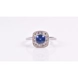 An 18ct white gold, diamond and sapphire cluster ring set with a cushion-cut sapphire of