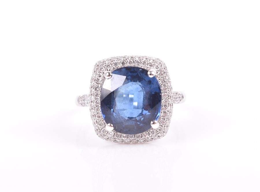 An 18ct white gold, diamond, and sapphire ring set with a cushion-cut blue sapphire of approximately