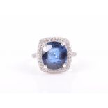 An 18ct white gold, diamond, and sapphire ring set with a cushion-cut blue sapphire of approximately