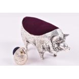 A novelty white metal pin cushion in the form of a pig 10 cm long, together with a small silver