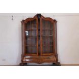 A mahogany display cabinet decorated with a carved portait and resting on clawfeet, Dutch, 19th