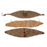 Three oval shaped Melanesian ornamentsof nassa shells, plant fiber and cotton ground. L. ca. 48