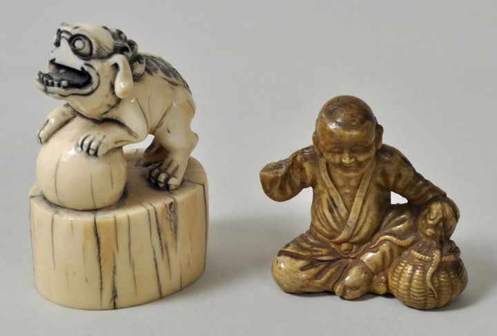 2 Netsuke, Japan, 19. Jh. a) Elfenbein, Fabeltier (Hund) auf einem Sockel mit eingeschnitzten